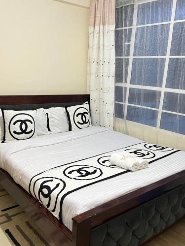 uma cama com lençóis pretos e brancos e uma janela em The comfort place Eldy em Eldoret