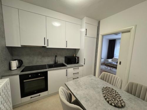 una cocina con armarios blancos y una mesa con sillas. en Estrada Apartment, en Sarajevo