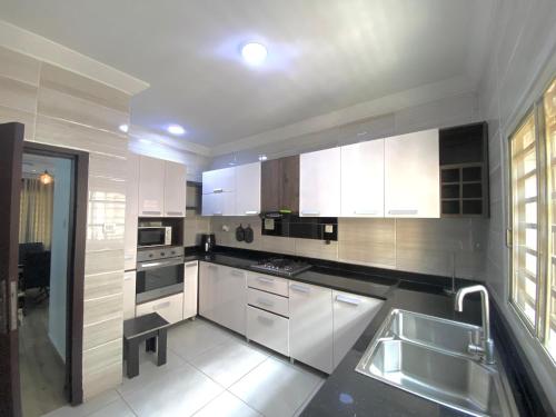 eine Küche mit weißen Schränken und einem Waschbecken in der Unterkunft Amazing Grace Apartment in Ikeja
