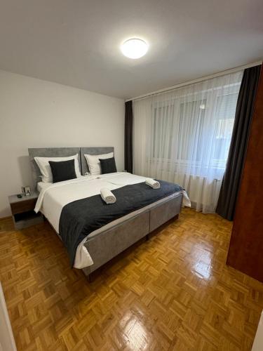 a bedroom with a large bed and a wooden floor at Estrada Apartment in Sarajevo