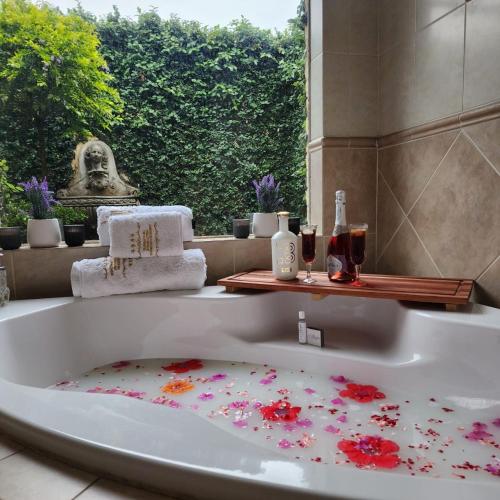 a bathroom with a bath tub with flowers on the floor at Royal Highness Lux Guesthouse in Carletonville