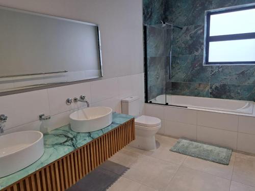 a bathroom with two sinks and a tub and a toilet at WavesEnd Wilderness Self-catering Units in Wilderness