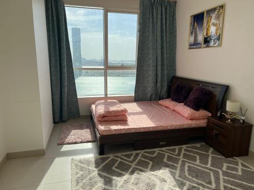 a bedroom with a bed and a large window at Burj Al saadah Al mamzar sharjah in Sharjah
