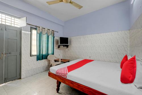 a bedroom with a bed with red pillows and a television at OYO Flagship Sai Ganesh Deluxe Lodge in Tirupati