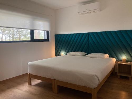 Schlafzimmer mit einem großen Bett mit blauem Kopfteil in der Unterkunft 45 Pines West in Açafora