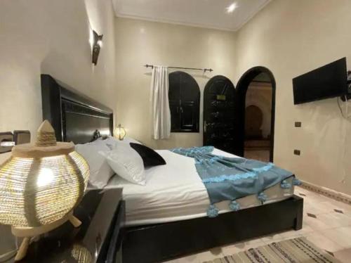 een slaapkamer met een groot bed en een televisie bij RIAD HANAFi in Marrakesh