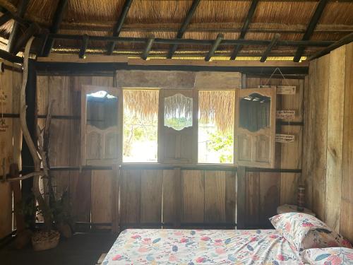 a bedroom with a bed and two windows at Punta Arena EcoHostal and EcoFit An Eco-Friendly Oasis for Adventurous Explorers and Serenity Seekers01 in Cartagena de Indias