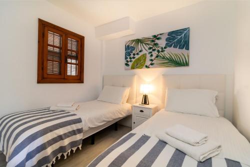 two twin beds in a room with a window at Villacana Community Family Beach Resort in Estepona