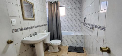 a white bathroom with a sink and a toilet at Habitación privada bombero garrido in Curicó