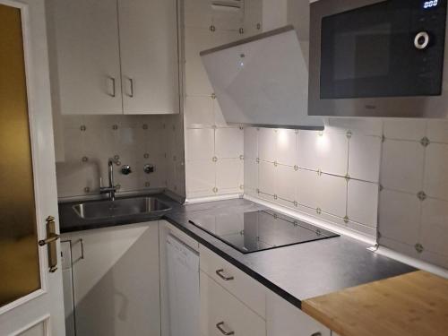 a white kitchen with a sink and a microwave at Piso turistico LAURSI in Burgos
