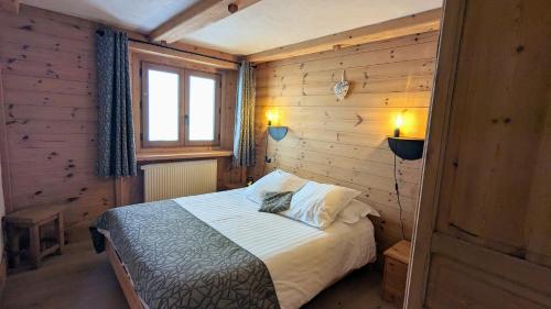 um quarto com uma cama num quarto de madeira em Chalet Lè Lodzé - Pieds des pistes em La Rosière