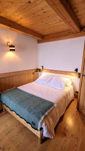 a large bed in a room with a wooden ceiling at Chalet Lè Lodzé - Pieds des pistes in La Rosière