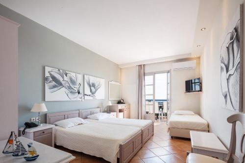 a white bedroom with two beds and a table at Kavuras Village in Agios Prokopios