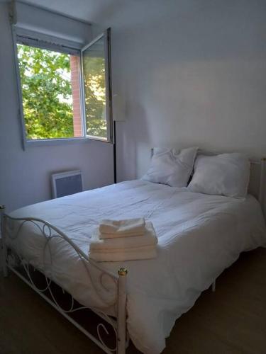 une chambre avec un lit blanc avec des serviettes dessus dans l'établissement Appartement cosy, à Cugnaux