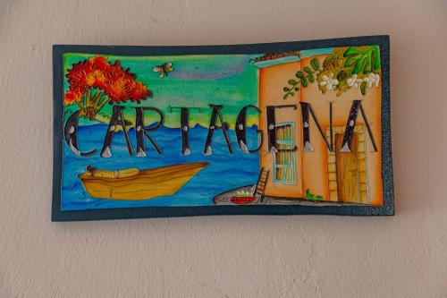 a painting of a house and a boat on a wall at Colonial Beach Airport Hotel in Cartagena de Indias