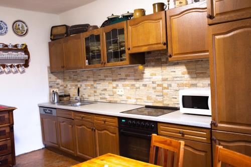 a kitchen with wooden cabinets and a white microwave at Chalupa na Valašsku in Halenkov