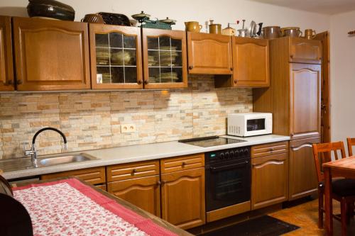 a kitchen with wooden cabinets and a sink and a microwave at Chalupa na Valašsku in Halenkov