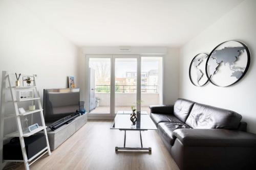 a living room with a couch and a tv at Spacieux appart JO2024 Parking Terrasse CDG 6 pers Wifi in Tremblay En France