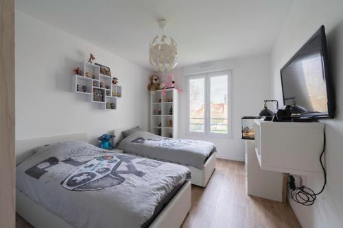 a bedroom with two beds and a tv in it at Spacieux appart JO2024 Parking Terrasse CDG 6 pers Wifi in Tremblay En France