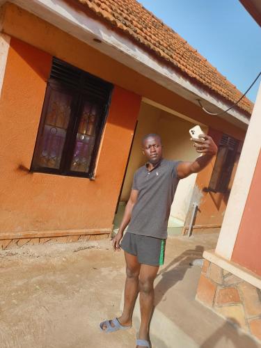 a man standing in front of a house at foxxies guest house in Buloba