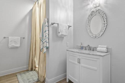 Baño blanco con lavabo y espejo en Hotel Pass Christian Queen Suite 205 en Pass Christian