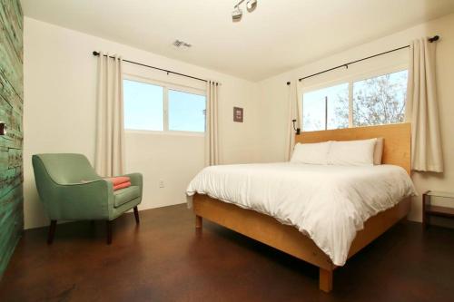 a bedroom with a bed and a green chair at Mayfair House - 4 Minutes to National Park! in Twentynine Palms