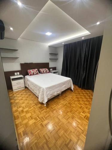 1 dormitorio con 1 cama y suelo de madera en Cobertura central /com ar, en Caxias do Sul