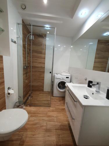 a bathroom with a shower and a sink and a washing machine at Apartament Widokowy Wisła in Wisła
