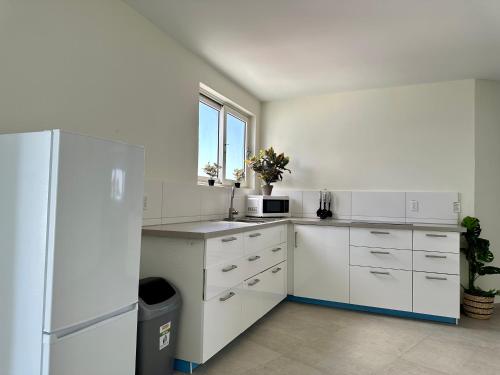 a white kitchen with a refrigerator and a window at MERAKII SEAVIEW ESCAPE CURACAO in Willemstad