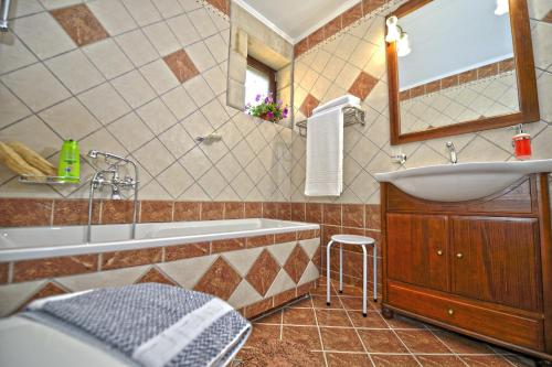 a bathroom with a tub and a sink and a mirror at Fotini Traditional Villas in Kavoúsion