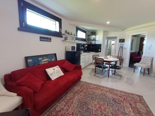 sala de estar con sofá rojo y cocina en Verde Mare Isola, en Carrozziere