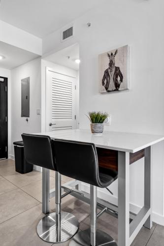 a kitchen with a white table and black chairs at Prime Location 1-Bed Retreat With Free Parking in Miami