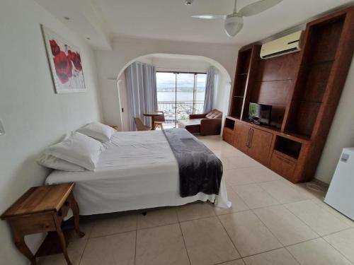 a bedroom with a large bed and a room with a balcony at HOTEL DAIFA in Florianópolis