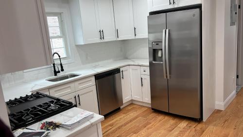 a kitchen with a stainless steel refrigerator and white cabinets at jfk 5 min away in Cedar Manor