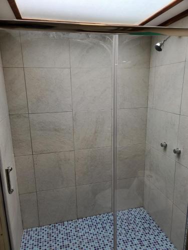 a shower with a glass door in a bathroom at Casita Luna de Miel in Nabón