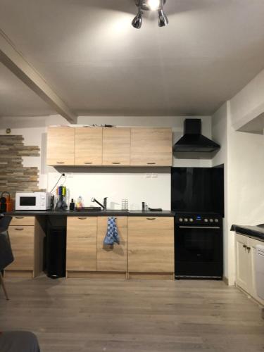 - une cuisine avec des placards en bois et des appareils noirs dans l'établissement maison de prescillia et frederic, à Boisset