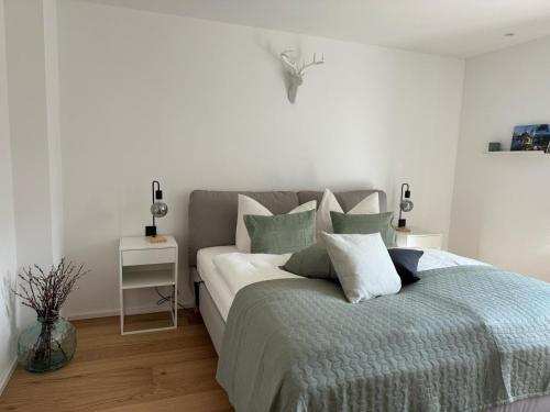 - une chambre dotée d'un grand lit avec des oreillers blancs et gris dans l'établissement Ferienwohnung Gschwendt, à Miesbach