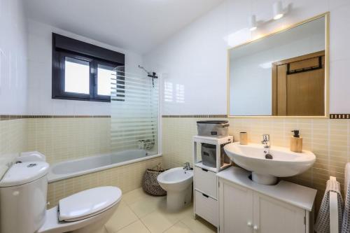 a bathroom with a sink and a toilet and a mirror at HolaOla HighClass Townhouse in Lajares