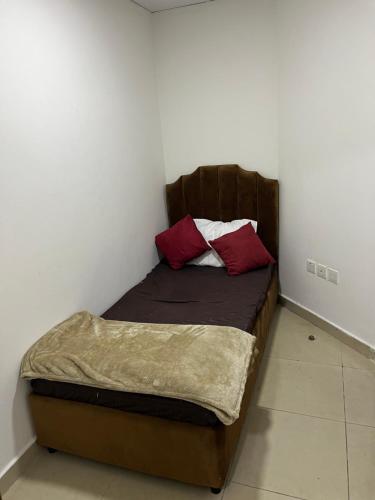 Una cama pequeña con dos almohadas rojas. en F30,R4,Single Room on the beach attach bath en Ajman 
