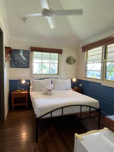 Grey Gum Lodge في نيمبين: غرفة نوم مع سرير والجدران الزرقاء والنوافذ