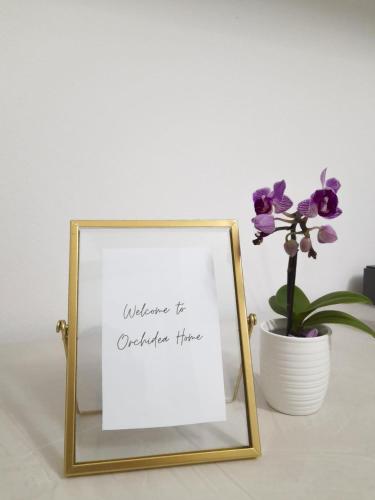 a picture frame sitting next to a vase with flowers at Orchidea Home in Ravenna