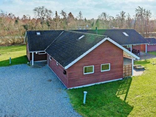 a large red barn with a black roof at 18 person holiday home in Idestrup in Marielyst
