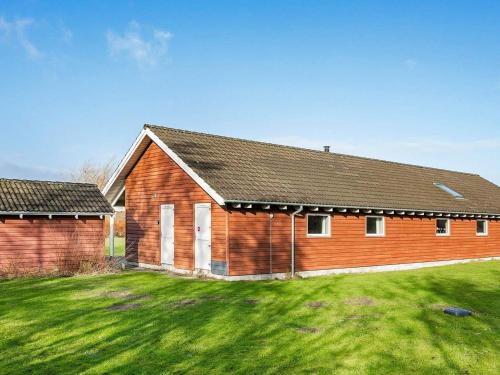 a large wooden building with a grass yard at 18 person holiday home in Idestrup in Marielyst
