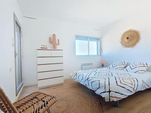 a white bedroom with a bed and a dresser at T2 vue mer accès direct plage le barcares in Le Barcarès