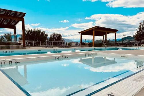 a large swimming pool with blue water and a gazebo at Kelowna family-friendly lake & Mountain view Luxury condo with AC, pool, Hot tub, near winery and shopping center in West Kelowna