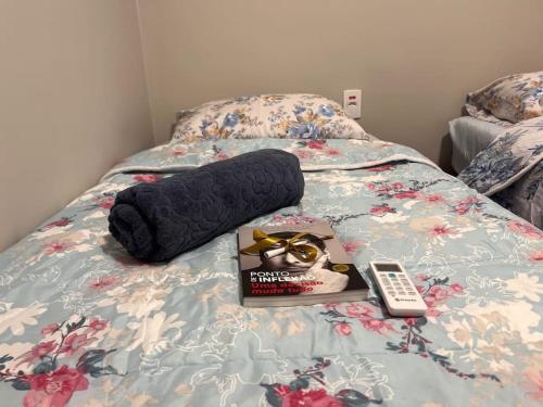 un libro y un mando a distancia en una cama en Charmoso e Acolhedor Espaço no Coração de BC, en Balneário Camboriú