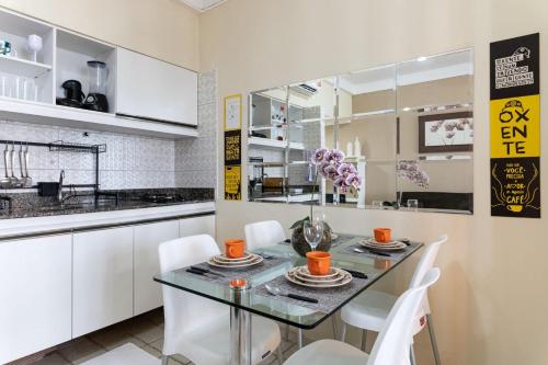 cocina con mesa de cristal y sillas blancas en Golden Beach Flat Recife, en Recife