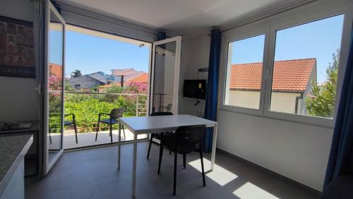 una mesa y sillas en una habitación con balcón en Guesthouse - Hotel California, en Novalja