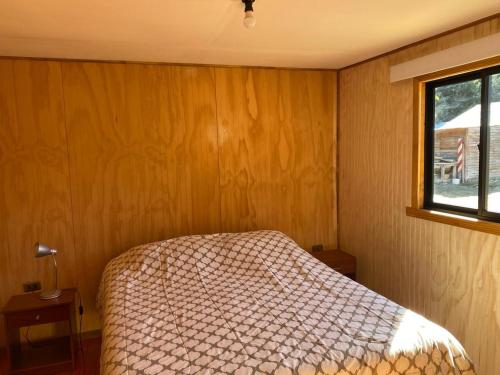 a bedroom with a bed and a window at Cabañas Captren Andino in Curacautín