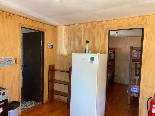 a kitchen with a white refrigerator and wooden walls at Cabañas Captren Andino in Curacautín